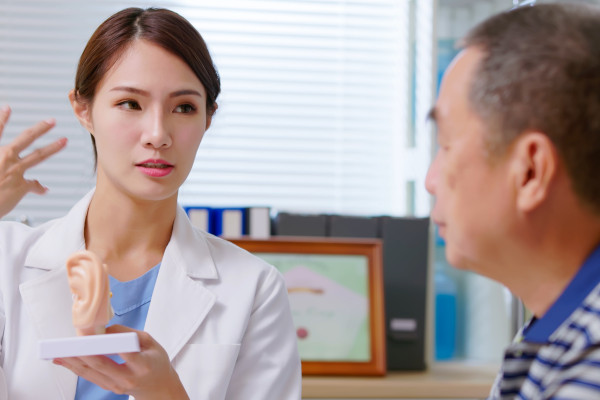 An audiologist explains ear-related health using an ear model