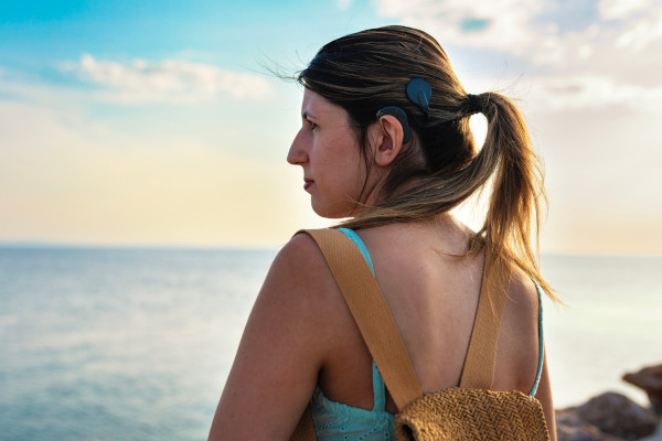 I woman looking out to the ocean while wearing her cochlear implant