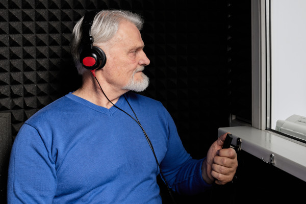 Senior man receiving a hearing test in a sound booth