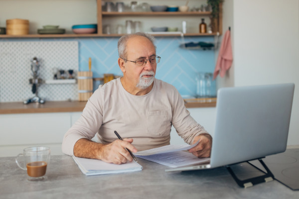 A man drinking a coffee while working on his laptop