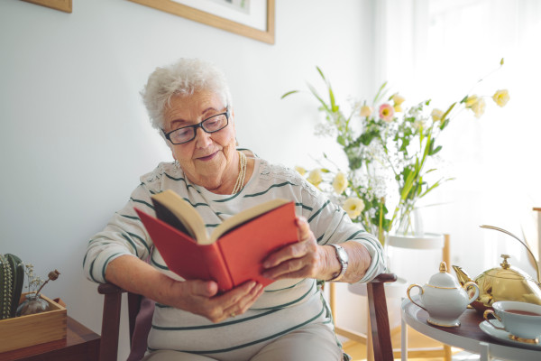 A senior reading alone in a brightly lit room