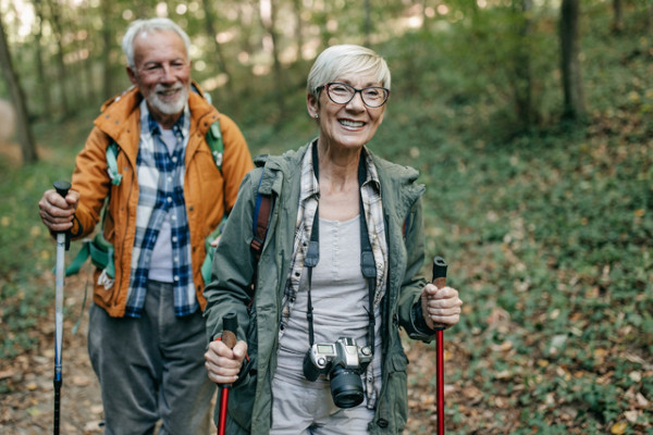 An older couple smiling while hiking together in the forest