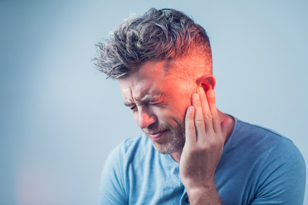 A man rubbing his ear due to tinnitus